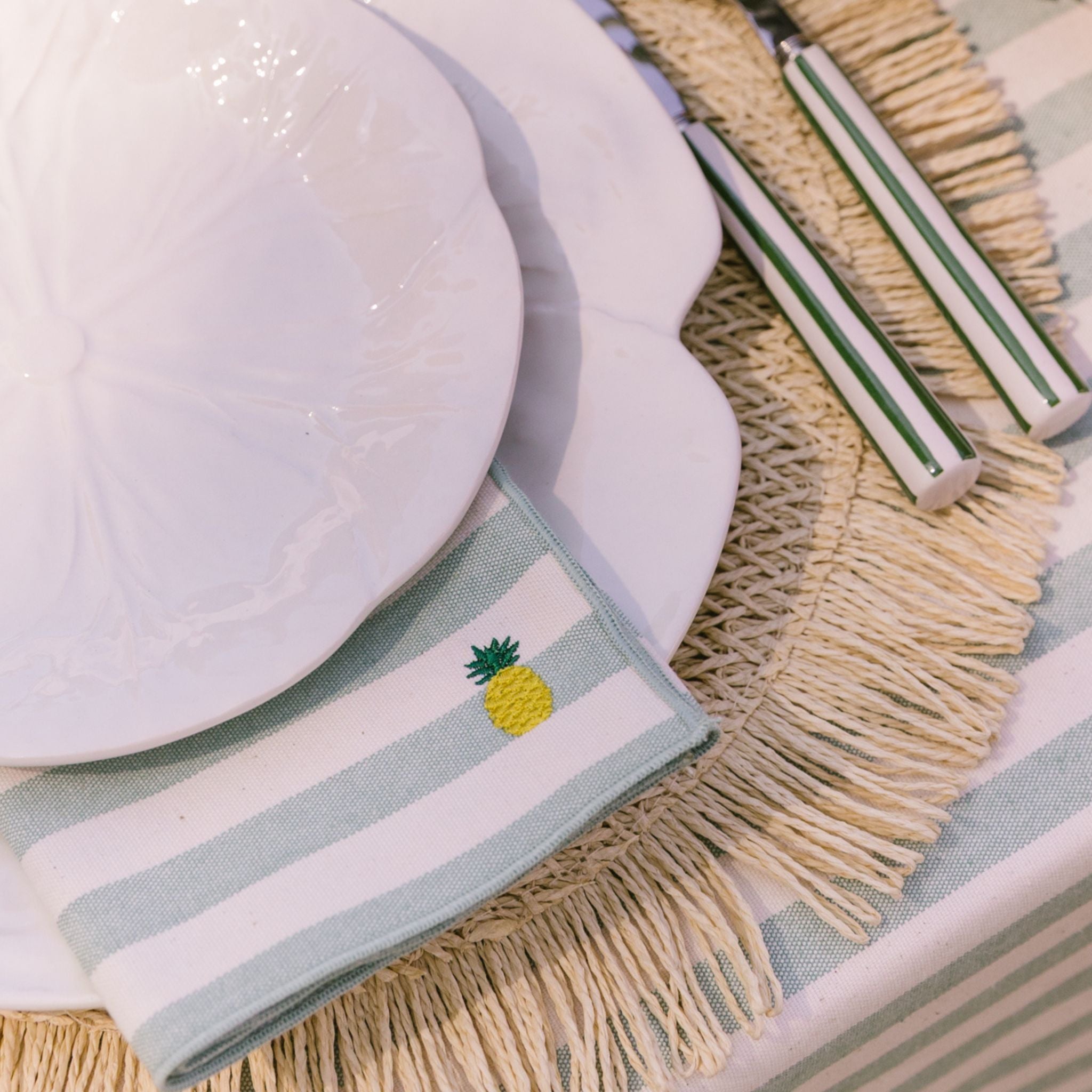 Napkin with pineapple design on a table setting with plates and cutlery.