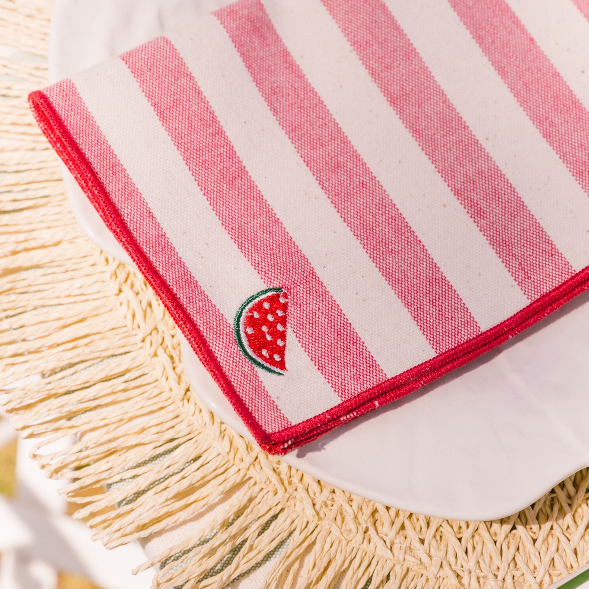 Striped napkin with watermelon design on a woven surface