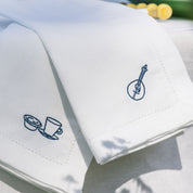 White napkins with blue embroidered designs on a white surface.