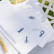 White napkins with blue embroidered designs on a white background