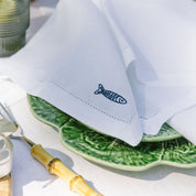 White napkin with a fish design on a green leaf-patterned plate